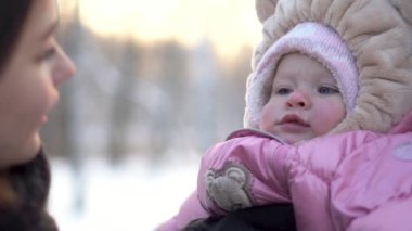 Mutlu, güzel anne bebek güzel kız kış Park, aile açık havada burun dokunmak için kapatın. Onun sevimli çocuk üzerinde bir kış ile neşeli anne portresi parkta yürümek.