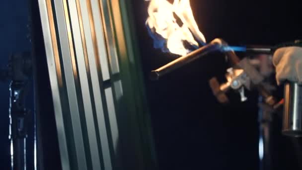 Brûlage d'un parement métallique gris avec torche au butane. dans l'obscurité. Gros plan .