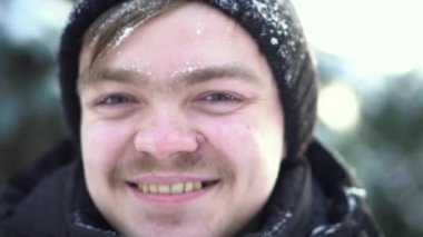 Bıyıklı yakışıklı, neşeli bir adam portresi ile onun yüzünde kar kış elbise giymiş. Güneşli bir kış günü gülümseyen mavi gözlü sarışın adam için Kapat.