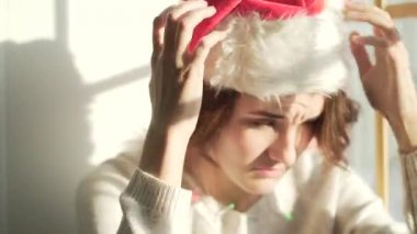Şampanya cam pencere üzerinde siting ve Santa Claus şapka koyarak genç gülümseyen kadın. Yakın çekim.
