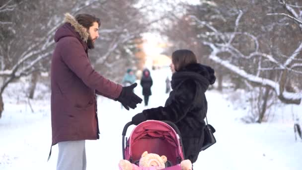 Young parents shouting at each other near a little baby in pink stroller while walking in winter park. Angry mother and father arguing outdoors, neglecting their child, young family problems. — Stock Video