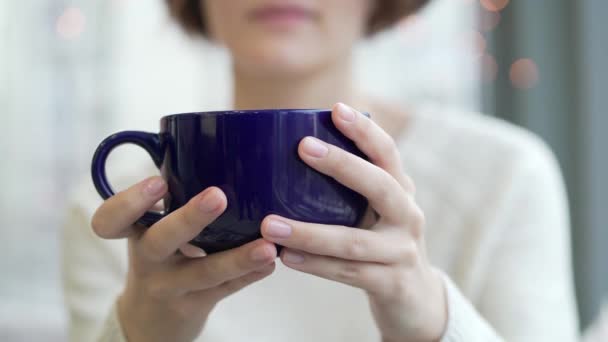 Zbliżenie: niebieską filiżankę kawy lub herbaty w dłoni dziewczyny. Świąteczną atmosferę. — Wideo stockowe