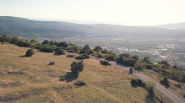 Motosikletçi ile dağlarda kırsal yolda gidiyor. Hisse senedi. Üstten görünüm, cliff motosikletçi geçtiğin Bayır Köyü arka plan üzerinde. Motosiklet yaz gezisi