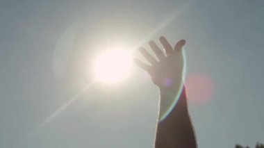 Güneş için ulaşan el Close-up. Hisse senedi. Adam sıcak parlak güneş ışınlarından gökyüzü zevk içinde için uzanıyor. Yüzme yaz güneşte