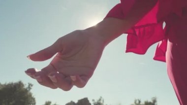 Yakın çekim parmağını otostop kaydolun. Hisse senedi. Güzel el otostop işareti göstermek için yükselir. Açık mavi gökyüzü güneşli karşı kırmızı elbiseli kadının el Close-up