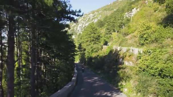 Vista superior do tráfego rodoviário de montanha. Estoque. Tráfego em pista de montanha no verão. Motociclista vai conhecer aventuras na estrada serpentina. Verão, férias, viagens e montanhas — Vídeo de Stock