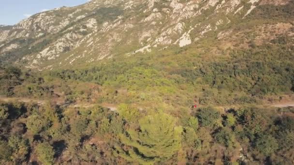 Vista superior de andar de moto casal. Estoque. Casal em passeios de moto na estrada rural entre contrafortes de floresta contra montanhas. Viagem romântica de verão em moto — Vídeo de Stock