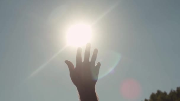 Güneş için ulaşan el Close-up. Hisse senedi. Parlak güneş ışığı uzanmış el parmaklarının arasından göğe tatili. — Stok video