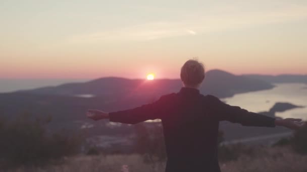 Rear view of man on background mountain river at sunset. Stock. Attractive man with admiration from seen landscape spread his hands to sides — Stock Video