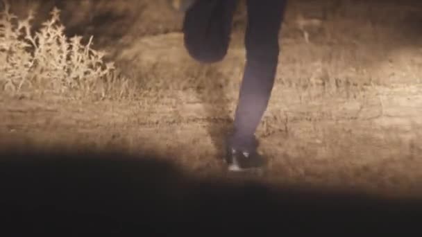 Man kör från jagar bil. Lager. Närbild av fötter av flyende hane i strålkastarna på natten i fältet — Stockvideo