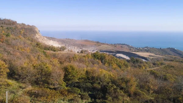 秋にマイニングの平面図です。ショット。秋の森と遠くの海の背景の山に掘られた鉱山の採石場します。 — ストック写真