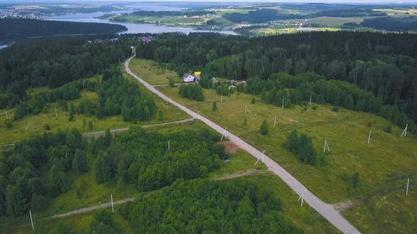 Top view of single house in forest. Clip. Remote house from town located in forest in calm and tranquility. Background is city on river shore in forest zone