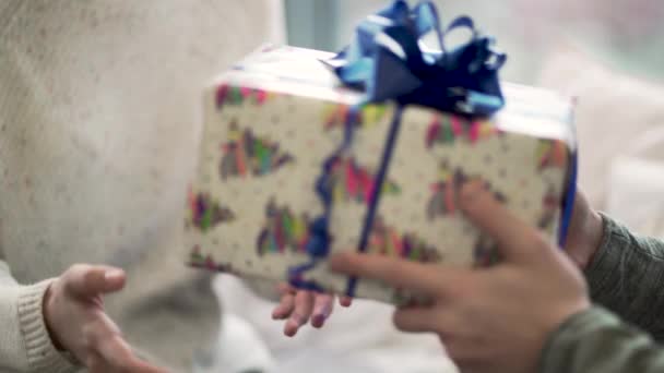 El primer plano del hombre pasa el regalo a la mujer. El tipo de cerca le dio a su novia Navidad o un regalo de año nuevo. Ambiente festivo de invierno — Vídeo de stock