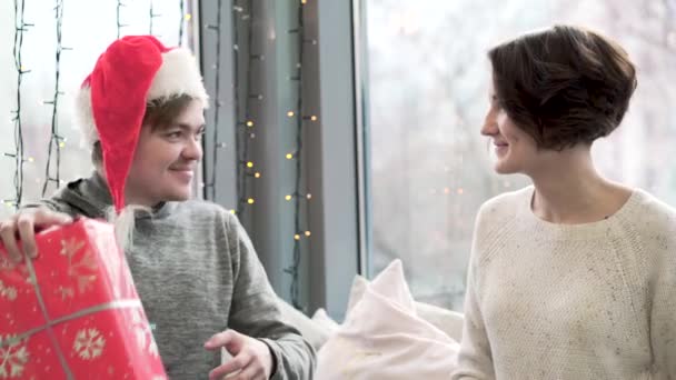 Young man and woman exchanged Christmas gifts. Couple in love exchanges gifts and spends Christmas holidays together. New year and Christmas holidays concept — Stock Video