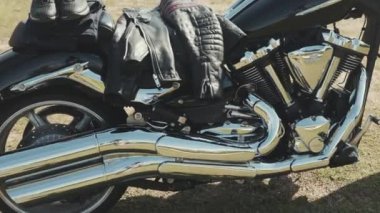 Krom motosiklet. Hisse. Üzerinde krom detaylar ve motosikletçi kıyafetleri olan yeni siyah motosikletin yan görüntüsü. Krom detaylar motosiklet yolculuktan önce bozkır manzarasını yansıtır