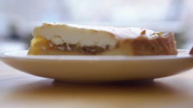 Closeup tabak peynirli kek. Yakın çekim el Beyaz plaka katmanlı cheesecake ile arka plan pencere üzerinde taşındı.