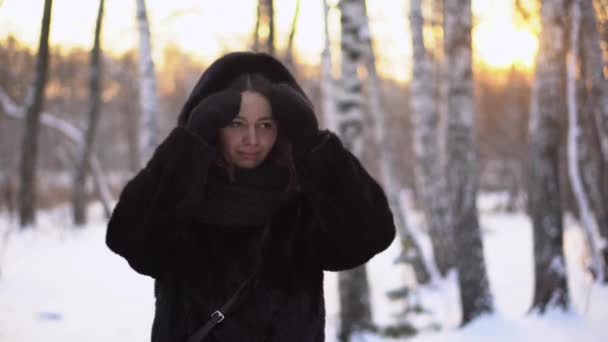 女人在公园里拉直头发 在冬天的小树林和阳光的背景下 年轻迷人的女人在寒冷中拉直头发 — 图库视频影像