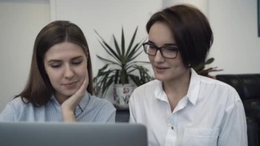İki iş kadınları ofiste dizüstü bilgisayar paylaşımı ve yeni proje tartışırken bir toplantıda. Yakın çekim.