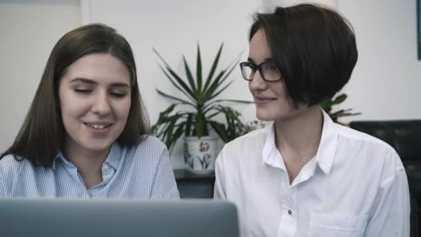 Dos empresarias en una reunión en la oficina compartiendo una computadora portátil y discutiendo un nuevo proyecto. Primer plano . — Vídeo de stock