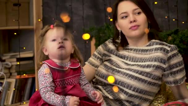 Porträtt av lycklig mor och bedårande barn i rummet dekorerad med grön Gran grenar och girlander. Mamma och söt baby flicka i vackra rum, familjefest koncept. — Stockvideo