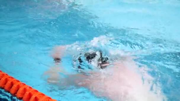 Primer plano para nadador profesional en mothion lento mientras bucea en la piscina cubierta. Entrenamiento de deportistas, buceo bajo el agua en la piscina . — Vídeos de Stock