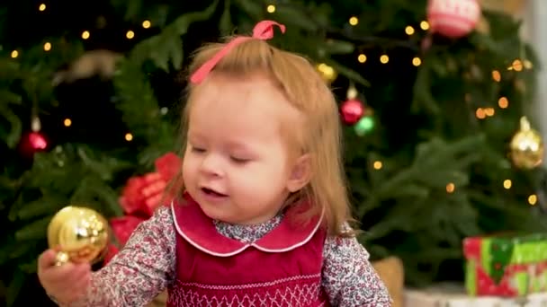 クリスマスの子供たち。かわいらしい子供の木の近く。クリスマスの子供。小さな女の子がおもちゃクリスマス ツリーの近くで遊んで — ストック動画