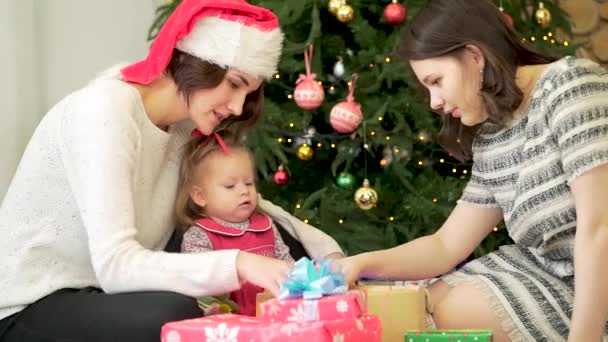 Bela família com duas mulheres sorridentes e criança perto da árvore de Natal. Jovem família lésbica com uma filha perto da árvore de Natal — Vídeo de Stock