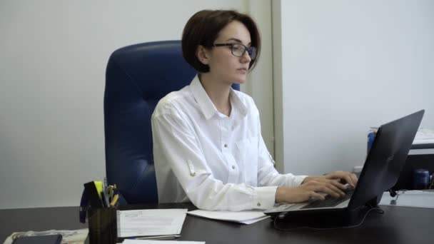 Encantadora joven en la informática de ropa formal en la oficina. Joven empresaria trabajando en una laptop en la oficina — Vídeos de Stock