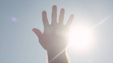 Güneş için ulaşan el Close-up. Hisse senedi. Parlak güneş ışığı uzanmış el parmaklarının arasından göğe tatili.