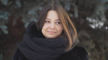 Kadın closeup Ladin kışın arka plan ile açık. Gözleri kahverengi ve gri eşarp ile siyah kürk paltolu şefkatle gülümsüyor ile genç çekici kadın görünüyor