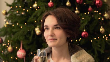 Genç kadın Noel ağacının yanında duran ve şampanya içmek. Noel ağacı arka plan üzerinde şampanya içmek güzel genç kadın