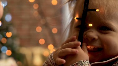 Çelenk onun elinde olan küçük kız. Şirin bir okul öncesi kız portre onun elinde ışıkların parlak çelenk ile yakın çekim