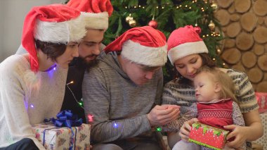 Yetişkin arkadaş Noel ağacı yanında küçük bir kız ile oynarken. Çocuk ile Noel ağacı yakınındaki dostça toplantılar