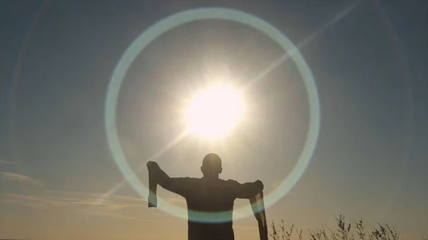 Vista posteriore dell'uomo che alza le mani al sole. Azioni. L'uomo in camicia lunga prega sul campo all'alba. Adorazione del sole — Foto Stock