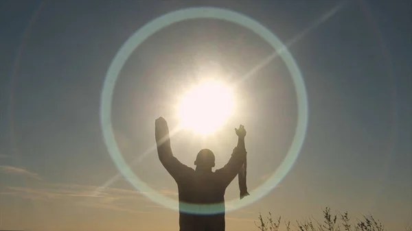 Vista posteriore dell'uomo che alza le mani al sole. Azioni. L'uomo in camicia lunga prega sul campo all'alba. Adorazione del sole — Foto Stock