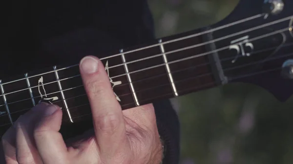 Close-up de mãos tocando baixo. Estoque. Mãos masculinas de guitarrista tocando acordes no baixo. Música executada na guitarra — Fotografia de Stock