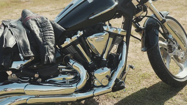 Moto cromado. Estoque. Vista lateral da nova motocicleta preta com detalhes cromados e roupas de motociclista deitado sobre ele. Chrome detalhes moto refletir paisagem de estepe antes da viagem — Fotografia de Stock