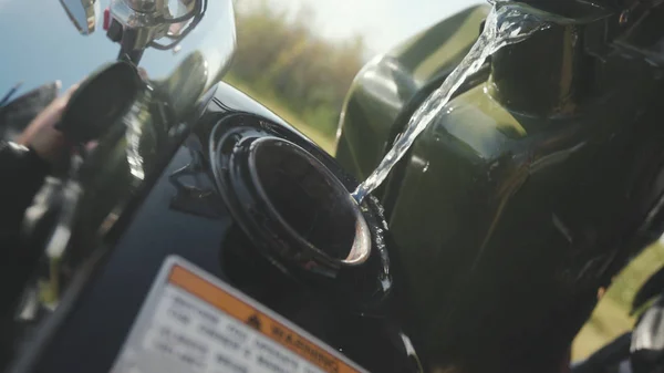 Close-up van opvulling benzine motor. Voorraad. Close-up van reflectie voor man in chrome detail van motorfiets. Motorrijder giet van jerrycan benzine in de tank. Voordat u verdergaat reis tanken — Stockfoto