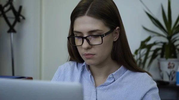Крупный план молодой женщины, работающей за компьютером в офисе. Привлекательная молодая бизнесвумен в очках усталая и сосредоточенная работа за компьютером в офисе — стоковое фото