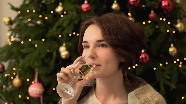 Giovane donna in piedi vicino all'albero di Natale e bere champagne. Bella giovane donna che beve champagne su sfondo albero di Natale — Foto Stock