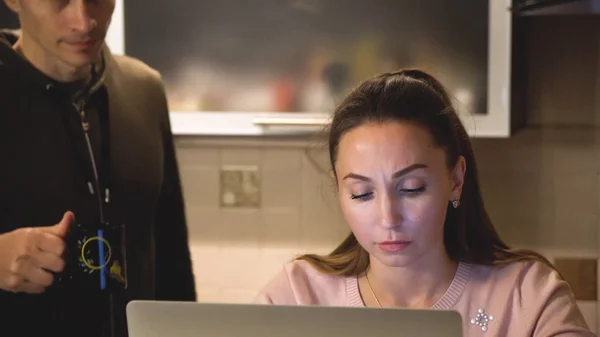 Tânăra muncitoare obosită lucrează cu computerul noaptea târziu, când iubitul ei îi aduce cafeaua. Solicitudine — Fotografie, imagine de stoc