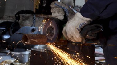 Erkek el nargile parçaları açısı öğütücü ile keser. Bir çelik inşaat alanında kıvılcım sıçraması ile kesme. Metal açılı taşlama kesim sırasında kıvılcım