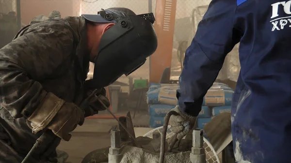 工厂工人用防护面罩和均匀的焊接金属。框架。一种人焊机在艰苦的加工过程中焊接金属与焊接机在车间. — 图库照片