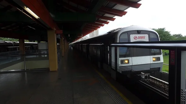 Um trem MRT em Cingapura na estação em fundo de árvores verdes. Atingido. Singapura massa trem rápido MRT na estação . — Fotografia de Stock