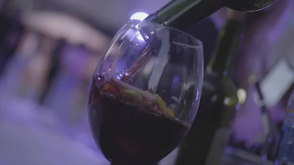 Sangria refrescante, soco com frutas e vinho tinto derramado no copo em câmera lenta. Moldura. Copo com frutas cítricas está sendo preenchido com vinho tinto . — Fotografia de Stock