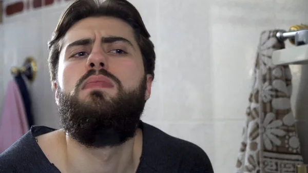 Ritratto di giovane adolescente che si guarda in uno specchio del bagno di casa facendo i capelli e preparandosi al mattino, interno della casa. bello unshaven uomo guardando in specchio — Foto Stock