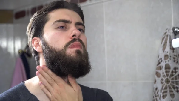 Handsome man using perfume in front of mirror. Handsome man applying perfume at the morning