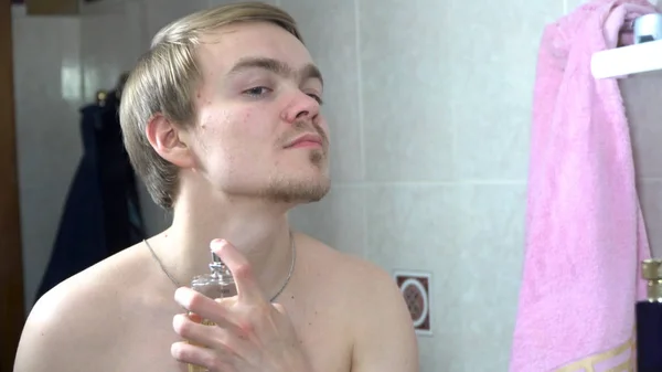 Pohledný muž používající parfém před zrcadlem. Pohledný muž použití parfému na ráno — Stock fotografie