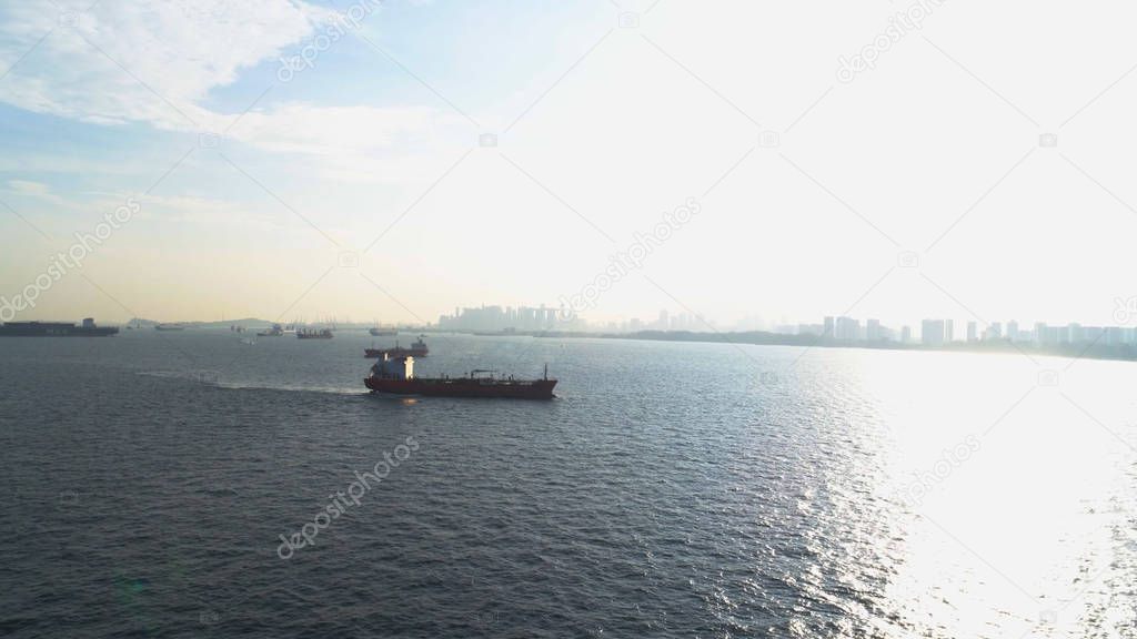 Industrial cargo ship sailing out at sea on beautiful coast background. Shot. Aerial view for large ship at sea and shore.