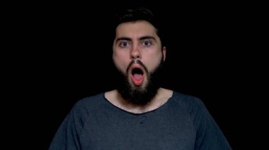 Şok, izole üzerinde siyah arka plan olmak adam, sıradan gri gömlek, dinleme cihazı gözlü görünüyor giymiş genç sakallı. Yüzünü dokunaklı şok genç adam